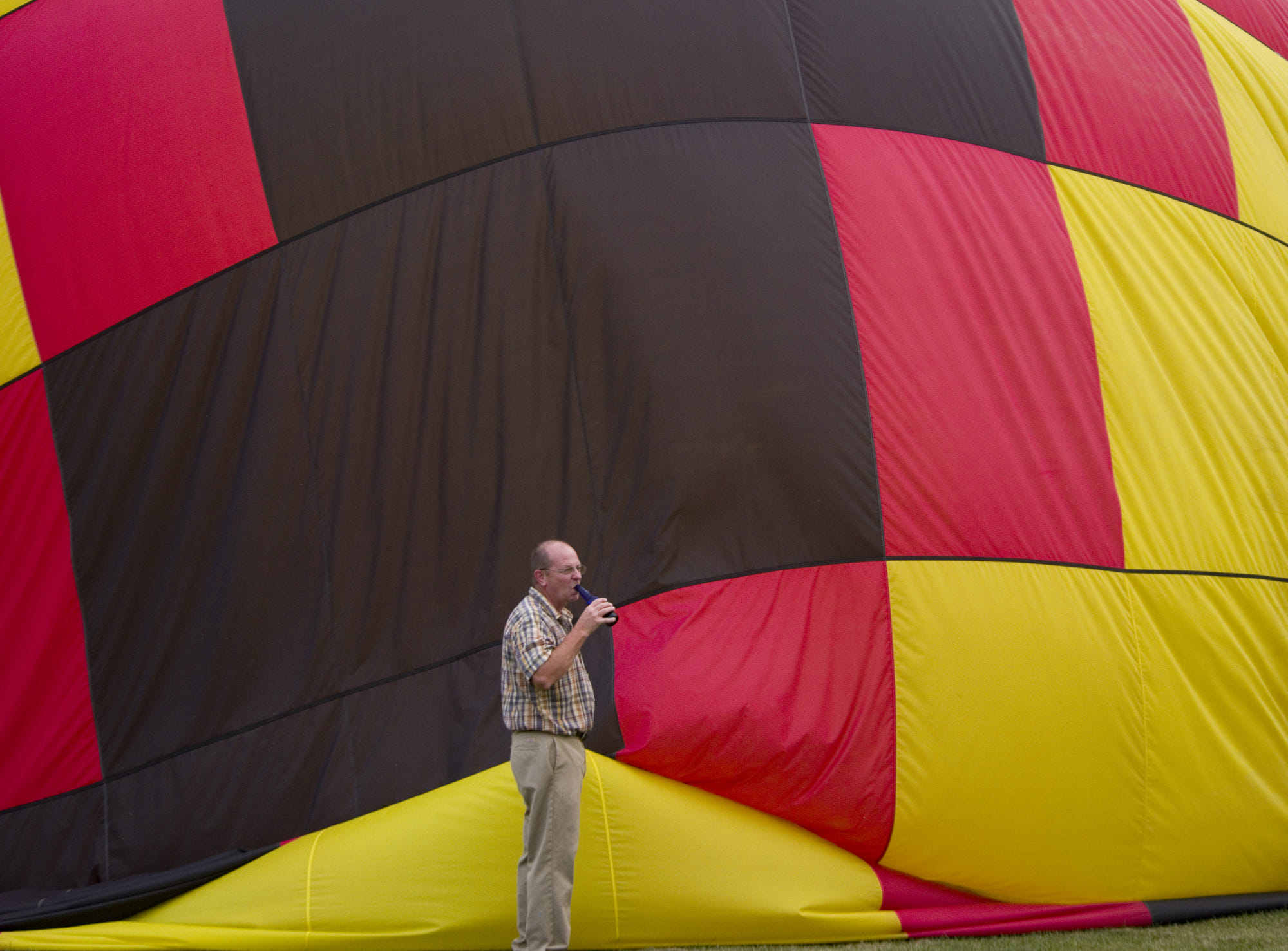 man drinking beer in front of deflating balloon