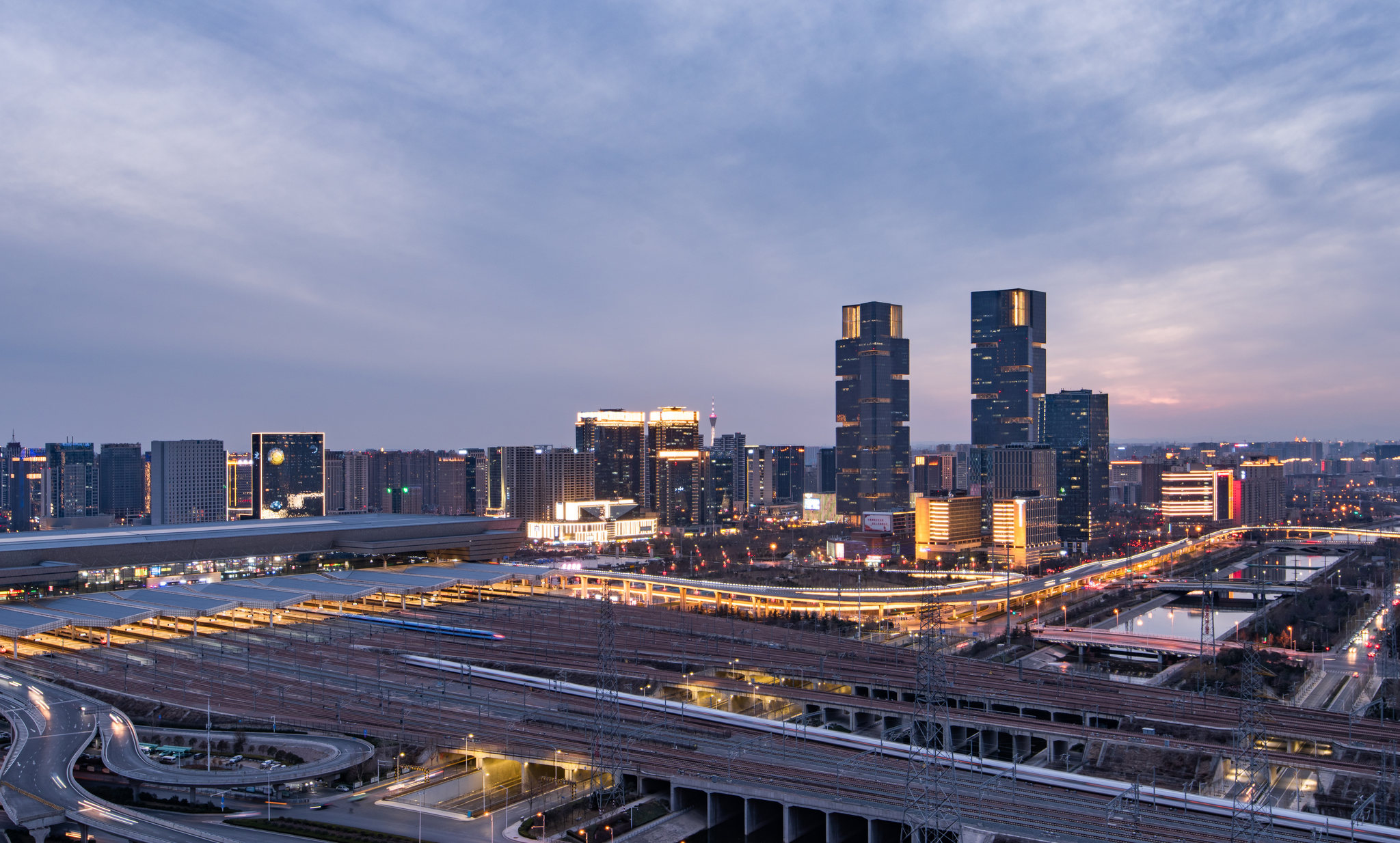 河南郑州郑东新区郑州东站高铁站金融区和绿地中心双子塔日落时分