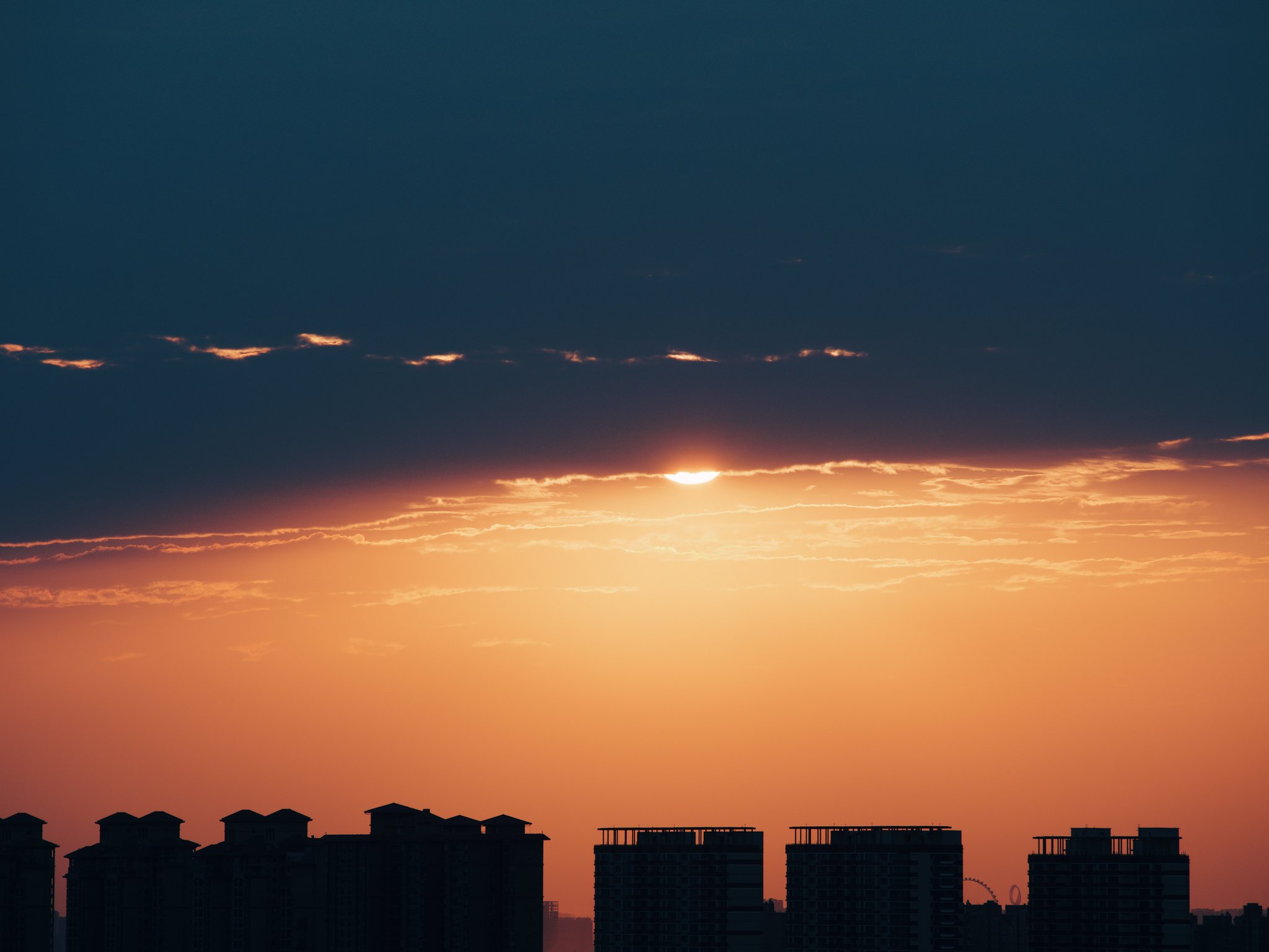 夕阳被云遮挡下的城市建筑剪影